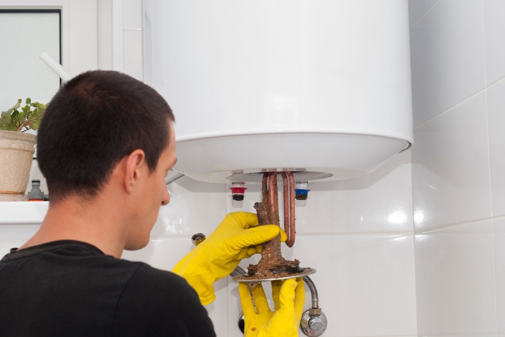 a man removing an electric heating ten from the water tank